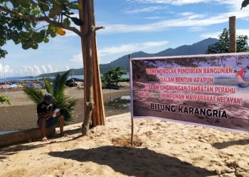 Baliho yang dipasang nelayan Karangria di lokasi proyek, berada di area tambatan perahu. (foto: ady/barta1)