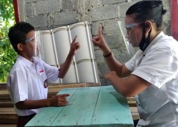 Ocen Hilda Lun mengajarkan bahasa isyarat saat belajar luring pada siswa tunarungu Meldo Malintoy di rumahnya