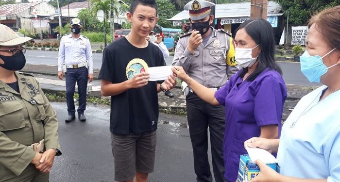 Petugas Gabungan memberikan masker gratis kepada masyarakat yang tidak memakai masker.