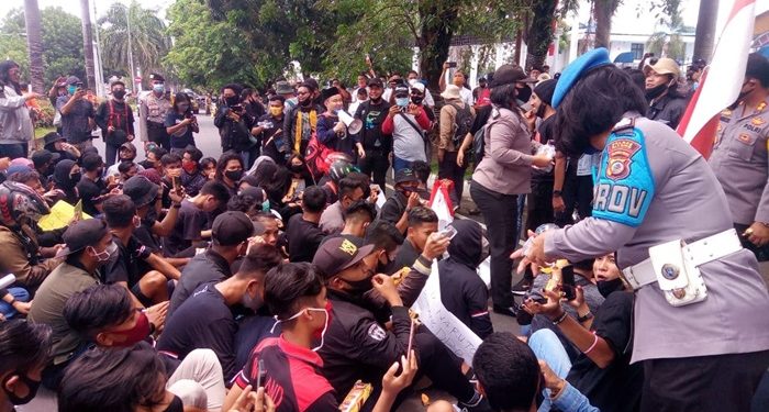 Polwan sedang membagikan roti dan air mineral kepada peserta Unjuk Rasa Menolak UU Omnibus Law