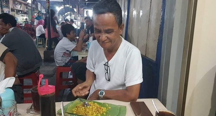 Almarhum Wakil Bupati Sangihe, Helmud Hontong, menikmati nasi kuning di Jalan Roda Manado. (Foto: istimewa)