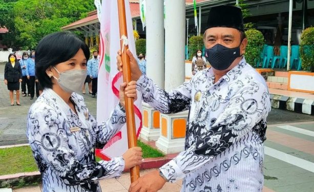 Bupati Jabes saat menyerahkan Panji PGRI kepada Ketua Umum PGRI Kabupaten Sangihe Yulien Manangkalangi