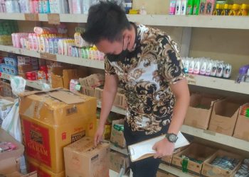 Petugas sedang mengecek ketersediaan bahan pokokdi toko