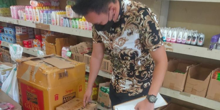 Petugas sedang mengecek ketersediaan bahan pokokdi toko
