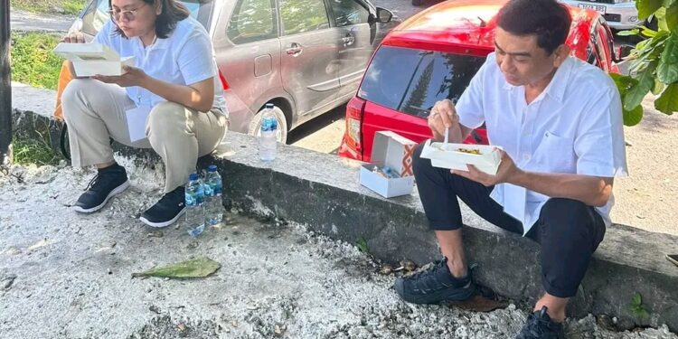 Pasangan Welly Titah dan Anisa Gretsya Bambungan sedang makan makanan kardus sambil duduk melantai (foto istimewa).