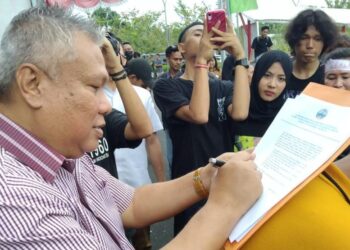 Anggota DPRD Provinsi Sulut, Amir Liputo saat menandatangani tuntutan masyarakat yang menolak Reklamasi. (Foto: istimewa)