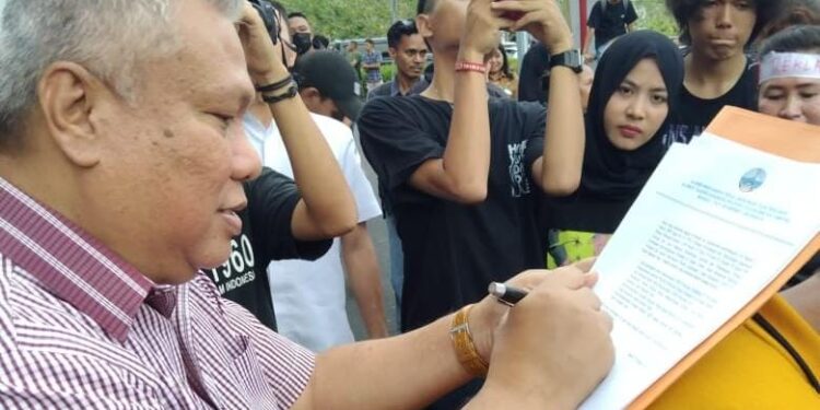 Anggota DPRD Provinsi Sulut, Amir Liputo saat menandatangani tuntutan masyarakat yang menolak Reklamasi. (Foto: istimewa)