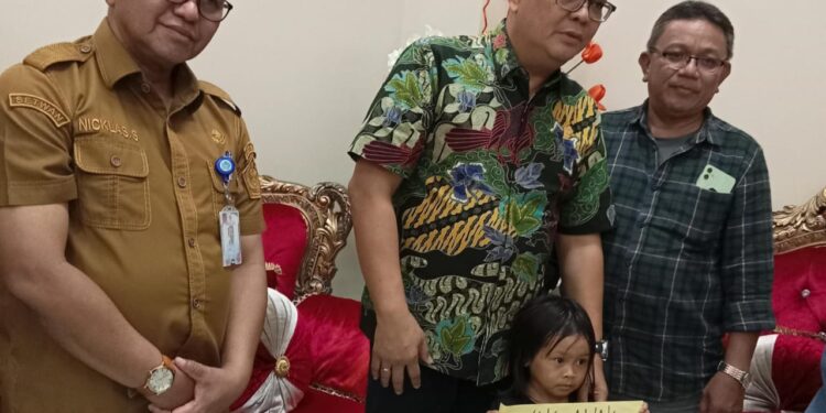 Wakil Ketua Komisi IV DPRD Provinsi Sulut, Louis Carl Schramm yang didampingi oleh PLT Sekwan Niklas Silangen beserta anak kecil yang orang tuanya menjadi bagian dari TPPO Kamboja. (Foto: meikel/barta)
