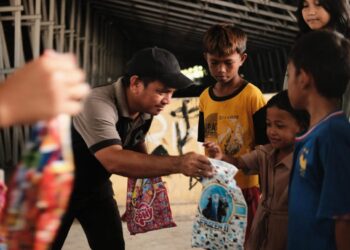 Ketua umum IKA Polimdo, Justman Entjaurau, ST., M.A.P saat membagikan bingkisan kepada anak-anak. (foto; istimewa)