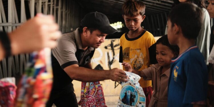 Ketua umum IKA Polimdo, Justman Entjaurau, ST., M.A.P saat membagikan bingkisan kepada anak-anak. (foto; istimewa)