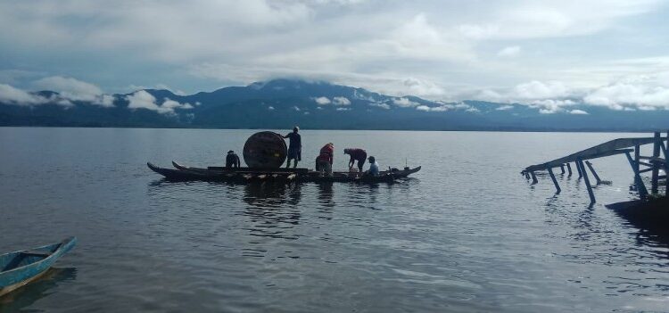 Proses Pengangkutan material untuk pembangunan jaringan listrik di Desa Olu dilakukan menggunakan kapal kayu tradisional melintasi danau. (Foto: Humas PLN)