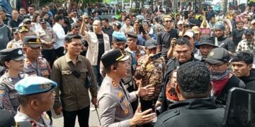 Kapolres Bitung AKBP Albert Zai, SIK, MH, melakukan negosiasi dengan para pengunjuk rasa di depan pintu masuk DPRD Kota Bitung. (foto: Chris/Barta1)