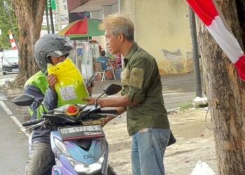 Penanggungjawab Pangan Gratis, Raymond Legi, membagikan pangan gratis bagi ojol. (foto: istimewa)