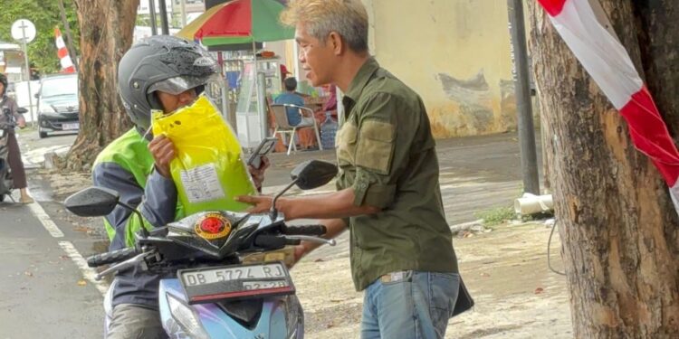 Penanggungjawab Pangan Gratis, Raymond Legi, membagikan pangan gratis bagi ojol. (foto: istimewa)
