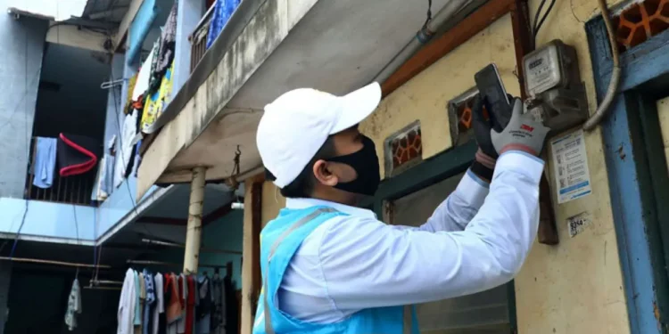 Petugas PLN melakukan pencatatan meter di rumah pelanggan. (foto: Tribunnews)