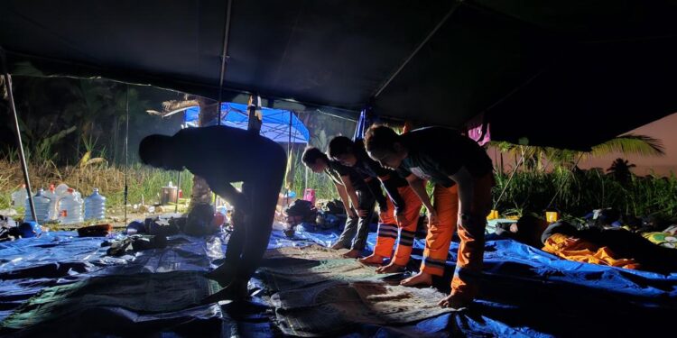 Petugas PLN tampak sedang beribadah di sela kerja tanpa henti menyalakan sistem kelistrikan pascabencana. (foto: Humas PLN)