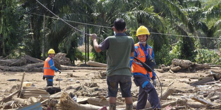 Senyum lebar Petugas PLN saat proses pemasangan kabel ke tiang jaringan listrik pengganti di kawasan terdampak bencana Sumatra. (foto: Humas PLN)