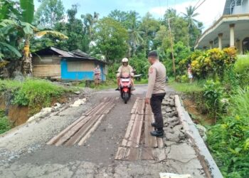 Foto: Kapolsek Manganitu IPTU Robert Supit saat memantau kondisi jalan rusak. (Dok. Istimewa)