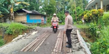 Foto: Kapolsek Manganitu IPTU Robert Supit saat memantau kondisi jalan rusak. (Dok. Istimewa)