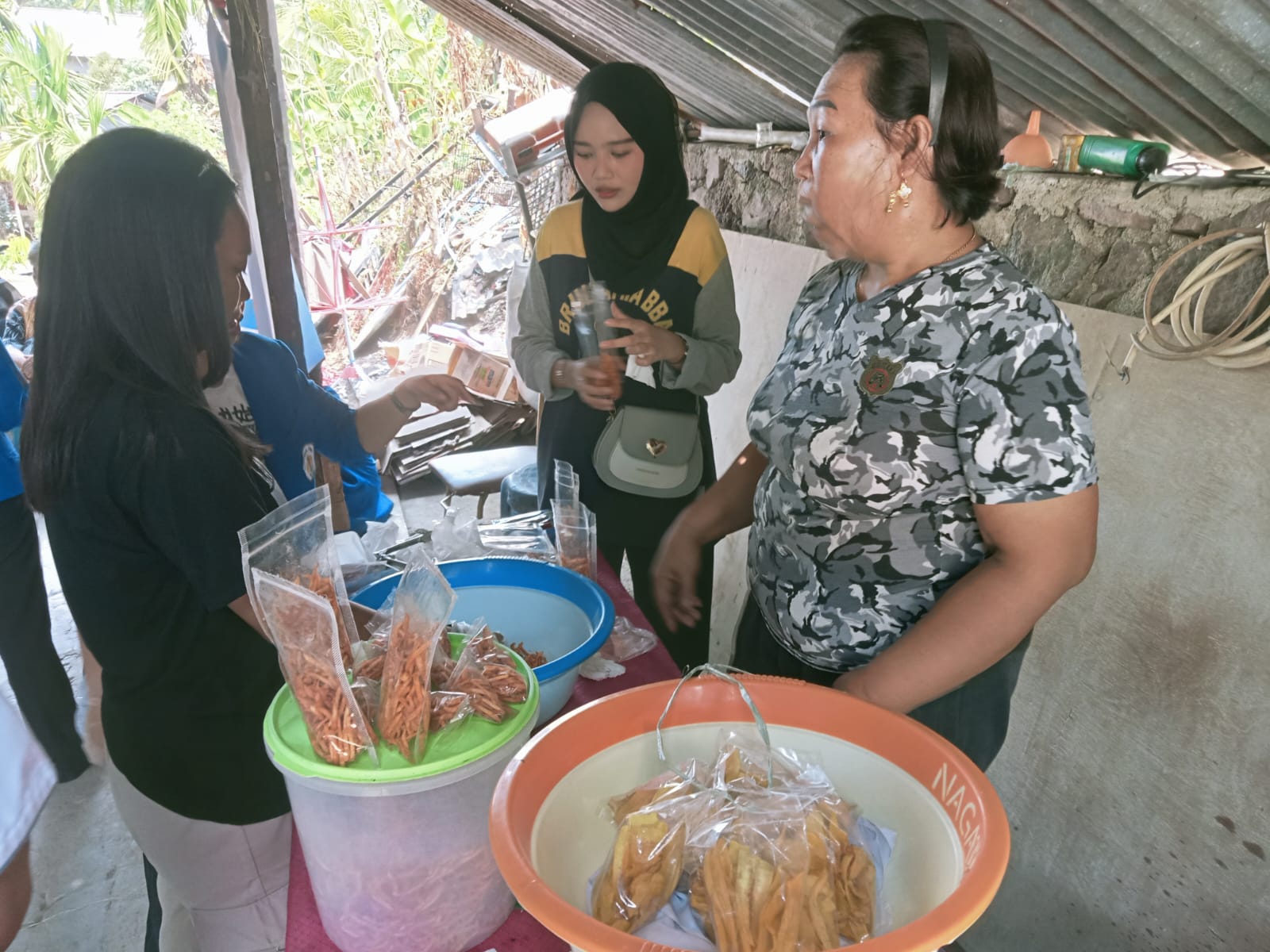 Proses mahasiswa dan dosen membantu mitra dalam mengisikan produk keripik ke wadahnya kemudian ditimbang. (foto : Meikel /Barta) 